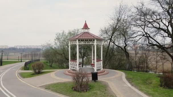 Şehir parkındaki çardak. Bir bisiklet yolu geçiyor. Çiçeksiz bahar parkı. — Stok video