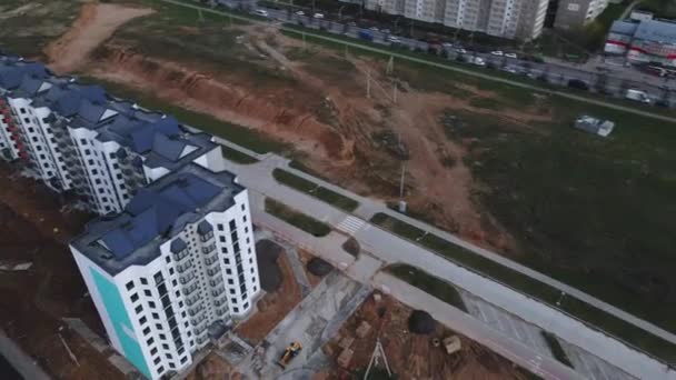 Le drone plonge au-dessus du nouveau quartier. Bâtiments à plusieurs étages, le chantier est visible. — Video