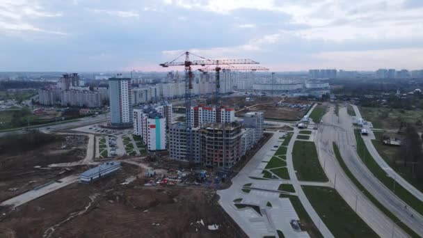 De drone vliegt naar de bouwplaats. Onafgewerkte huizen en torenkranen zijn zichtbaar. Stadsontwikkeling met meerdere verdiepingen. — Stockvideo