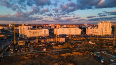 Şafakta inşaat alanında. Çok katlı evler görülebiliyor. İnşaat vinçleri ve komşu yerleşim yerleri. Panoramik hava fotoğrafçılık.