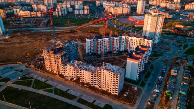 Şafakta inşaat alanında. Çok katlı evler görülebiliyor. İnşaat vinçleri ve komşu yerleşim yerleri. Panoramik hava fotoğrafçılık.