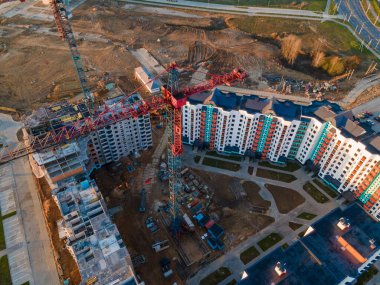 Şafakta inşaat alanında. Çok katlı evler görülebiliyor. İnşaat vinçleri ve komşu yerleşim yerleri. Panoramik hava fotoğrafçılık.
