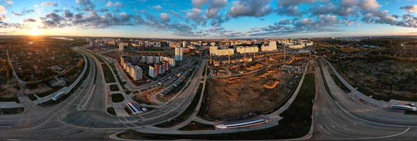 Construction site at dawn. Claimed multi-storey houses are visible. Construction cranes and neighboring urban quarters. Panoramic aerial photography.