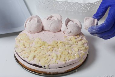 Bir kadın lokum keki hazırlar. Dekorasyon ve pasta için marşmelovdan güller yapıyor. Maske ve eldivenle çalışıyor..