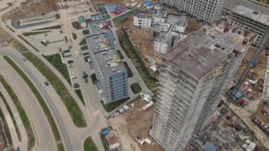 Büyük bir inşaat alanı. Şehir merkezinde inşaat halindeki çok katlı binalar. Kamerayı kaldırıp döndürerek uçmak. Hava video çekimi.