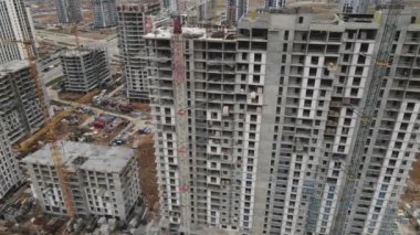 İnşaat alanının üzerinden uçuş. İnşaat halindeki yüksek binalar ve inşaat vinçleri aşağıda görülebiliyor. Yana doğru uçuyor. Hava fotoğrafçılığı.
