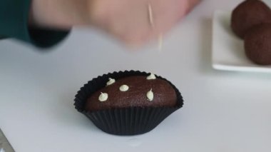Kadın patatesli kek yapıyor. Pastalar masanın üstünde. Bir kadın pasta poşetinden krema sürüyor.