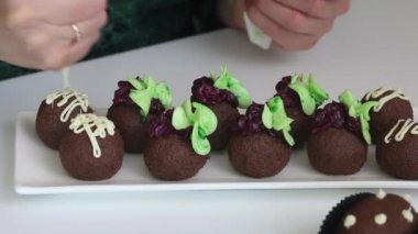 Kadın patatesli kek yapıyor. Pastalar masanın üstünde. Bir kadın pastaları çikolatayla süslüyor. Yakın çekim..