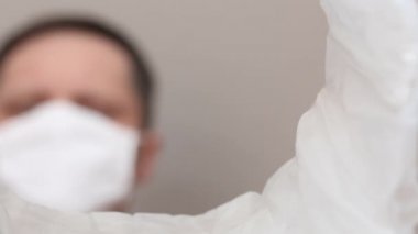 Tıbbi maskeli bir adam kullanılmış pilleri çöp kutusuna atıyor. Bir çöp konteynırının içinden çekilmiş. Eli yakın plan çekilmiş..