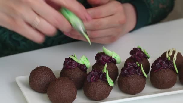 Woman makes a brownie Potato. The cakes are on the table. A woman decorates pastries with cream from a pastry bag. Close-up shot — Stock Video