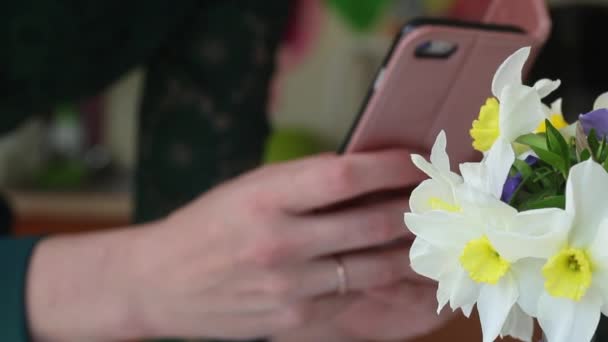 La chica toma un ramo de narcisos por teléfono. Las flores se disparan en primer plano.. — Vídeo de stock