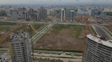 Modern şehir gelişimi. İnşaat alanında çok katlı binalar inşa ediliyor. İnşaat çalışmaları devam ediyor. Kamera açıkken uçmak. Hava fotoğrafçılığı.