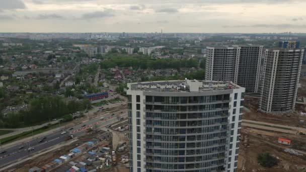 Moderno sviluppo urbano. Cantiere con edifici a più piani in costruzione. I lavori di costruzione sono in corso. Le cime degli edifici sono visibili. Videografia aerea. — Video Stock