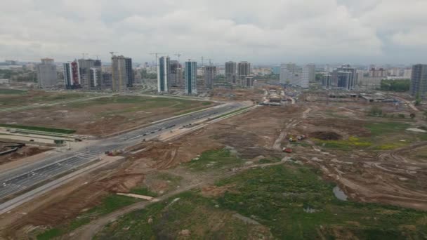 Local de construção com edifícios de vários andares em construção. Desenvolvimento urbano moderno. Os trabalhos de construção estão em andamento. Voe de volta com rotação de câmera. Videografia aérea. — Vídeo de Stock