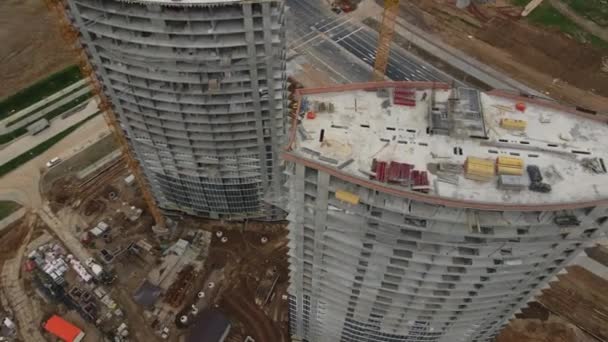 Modern urban development. Construction site with multi-storey buildings under construction. Construction work is underway. The camera is down. Aerial videography. — Stock Video