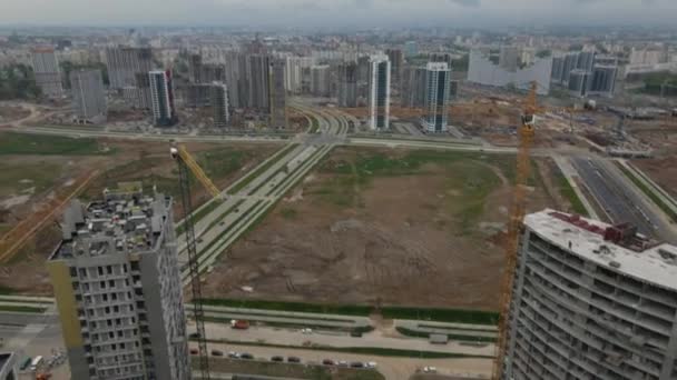 Moderno sviluppo urbano. Cantiere con edifici a più piani in costruzione. I lavori di costruzione sono in corso. Volare con la telecamera abbassata. Fotografia aerea. — Video Stock