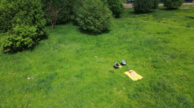 Yeşil bir çayırda güneşlenen bir kadın. Sarı bir halıda, karnının üstünde yatıyordu. Hava fotoğrafçılığı.