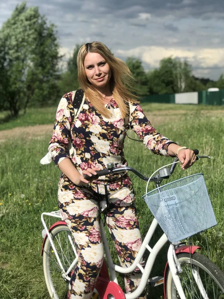 Bisiklet üzerinde poz veren eşofmanlı bir kız. Parktaki çimenlikte.