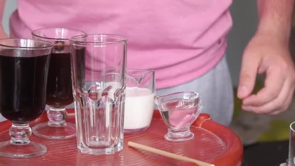 Faire un latte glacé bleu. L'homme verse de la glace dans le verre. Il y a d'autres ingrédients sur le comptoir à côté. Gros plan. — Video