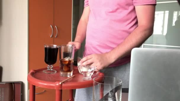 A fazer um Latte de Gelo Azul. Um homem está a adicionar creme a um copo de bebida. Há outros ingredientes no balcão ao lado dele. — Vídeo de Stock