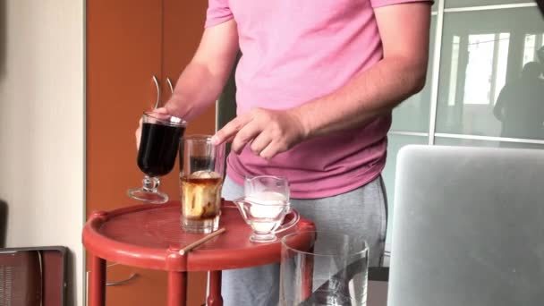 Einen Blue Ice Latte machen. Ein Mann fügt einem Glas Schnaps Alkohol hinzu. Daneben liegen weitere Zutaten auf der Theke. — Stockvideo