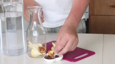 Adam elmaları kesiyor ve şişeye atıyor. Baharat ekliyor. Detoks suyu hazırlanıyor. Elma, tarçın ve anason. Elma ve baharatla karıştırılmış pişirme suyu. Yakın çekim..