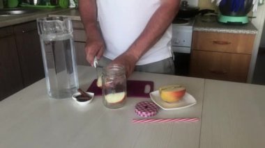 Adam elma kesiyor. Detoks suyu hazırlanıyor. Elma, tarçın ve anason. Elma ve baharatla doldurulmuş yemek suyu.