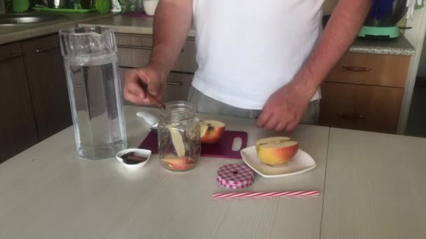 Un homme ajoute des épices à un pot de pommes tranchées. Préparation de l'eau de désintoxication. De pommes, cannelle et anis. Eau de cuisson infusée de pommes et d'épices. — Video