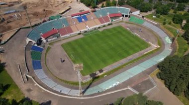Şehir parkındaki futbol stadyumu. Yakınlarda yeni bir arena inşa ediliyor. Yeşil bir alan ve stantlar görülebilir, farklı renklerde boyanmış. Yana doğru uçuyor. Geri geri uç. Hava fotoğrafçılığı.