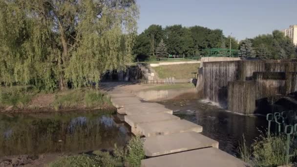 Fontanny i kaskady nad rzeką. Wokół jest dużo zieleni. Lot nad miejskim zbiornikiem wodnym na małej wysokości. Fotografia lotnicza — Wideo stockowe