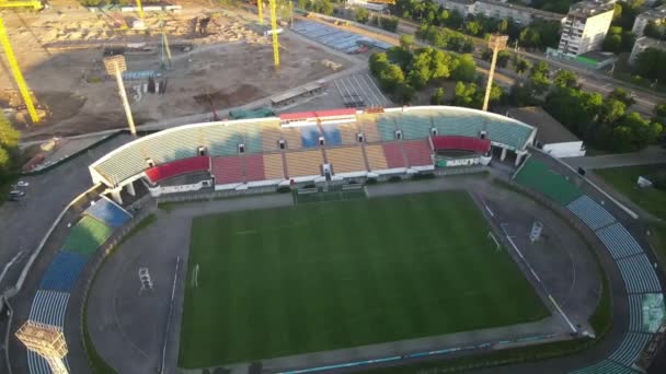 Şehir parkındaki futbol stadyumu. Yeşil bir alan ve stantlar görülebilir, farklı renklerde boyanmış. Güneşin doğuşunda. Hava fotoğrafçılığı — Stok video