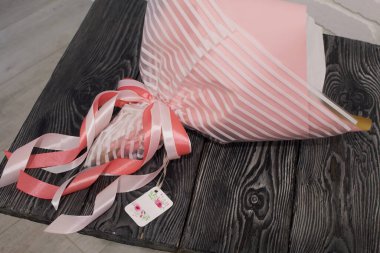 Buket folyo ve el işi kağıdına sarılı. Kurdeleler ve etiketler görünür. Sevdiklerine bir hediye..