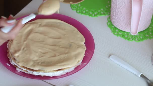 Kadın pasta katmanlarını üst üste istifliyor. Kremayla kayganlaştırıyor. Pasta yapmak için gerekli malzemeler. — Stok video