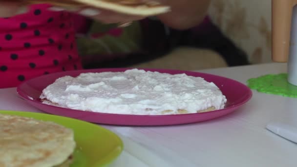 Uma mulher espalha creme nas camadas de bolo. Pilhas camadas uma em cima da outra. Ingredientes próximos para fazer o bolo — Vídeo de Stock