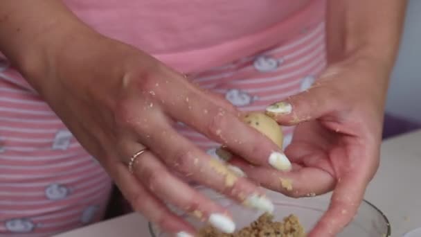 Een vrouw rolt bolletjes pindakaas, chocolade en kokosmeel. Plaatst in papieren taartjes. Gezonde snoepjes. Close-up opname. — Stockvideo