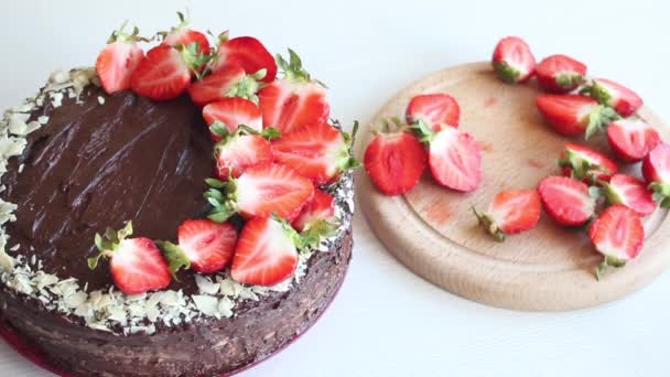 Una mujer decora un pastel con fresas. Cocinar pastel de chocolate con cacahuetes y fresas. Primer plano de disparo. — Vídeos de Stock