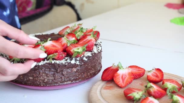 Een vrouw versiert een taart met aardbeien. Chocoladetaart met pinda 's en aardbeien. Close-up opname — Stockvideo