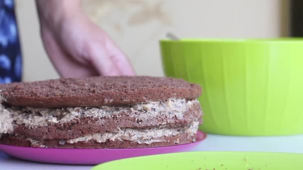 Una mujer está cubriendo pasteles de galletas con crema. Cocinar pastel de chocolate con cacahuetes y fresas. — Vídeos de Stock