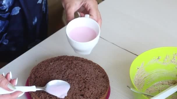 Eine Frau imprägniert Plätzchen mit Erdbeerlikör. Schokoladenkuchen mit Erdnüssen und Erdbeeren kochen. — Stockvideo