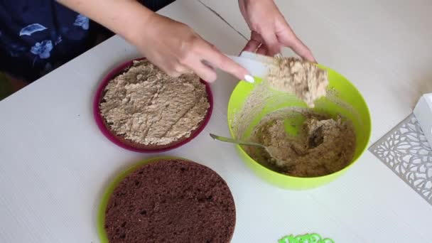 Una mujer unta un pastel de galletas con crema. Filmado desde arriba. Cocinar pastel de chocolate con cacahuetes y fresas. — Vídeos de Stock