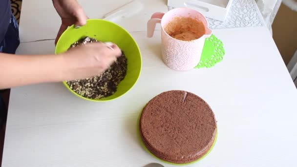 Uma mulher mistura amendoins e chocolate em um recipiente. Faz amendoim e creme de bolo de chocolate de morango. Os ingredientes para cozinhar são colocados sobre a mesa. — Vídeo de Stock