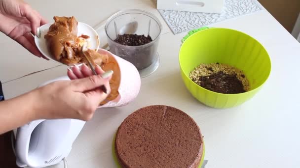 Bir kadın fıstık ve çilekli çikolatalı pasta için krema yapar. Yemek pişirmek için gerekli malzemeler masanın üzerine serildi... — Stok video