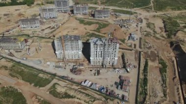 Modern bir şehir bloğunun inşaatı. İnşaat alanında binaların beton çerçeveleri görülebiliyor. İnşaat vinçleri çalışıyor. Hava fotoğrafçılığı.