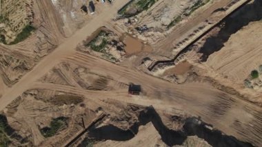 Modern bir şehir bloğunun inşaatı. İnşaat alanında toprak yollar kesişiyor. Kamyon hareket ediyor. Hava fotoğrafçılığı.