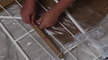 Adam çömelmiş, rafları boşaltıyor. Filmi ve ambalajı bıçakla kesiyor. Kendini izole etme sırasında ev işleri. Yakın çekim...