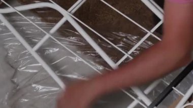 Adam çömelmiş, rafları boşaltıyor. Filmi ve ambalajı bıçakla kesiyor. Kendini izole etme sırasında ev işleri. Yakın çekim.