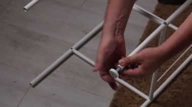 Adam rafları topluyor. Bacakları metal rafa yerleştirir. Yakın plan çekim. Kendi kendini izole ederken ev ödevi.