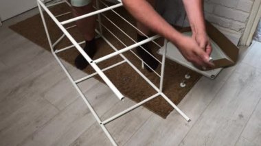 Adam rafları topluyor. Bacakları metal rafa yerleştirir. Kendi kendini izole ederken ev ödevi.