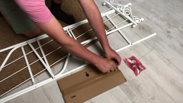 The man is squatting, unpacking the rack. She cuts the film and packaging with a knife. Household chores during self-isolation.. — Stock Video