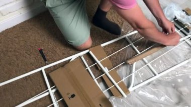 Adam çömelmiş, rafları boşaltıyor. Filmi ve ambalajı bıçakla kesiyor. Kişisel izolasyon sırasında ev işleri.